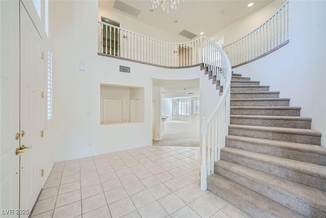 entryway with visible vents, stairway, a towering ceiling, and light tile patterned flooring