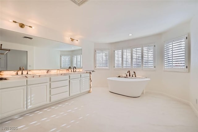 full bath featuring double vanity, a soaking tub, visible vents, a sink, and baseboards