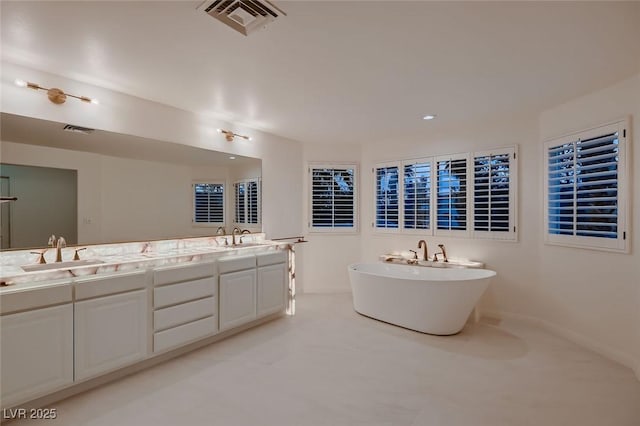 full bath with double vanity, a soaking tub, visible vents, and a sink