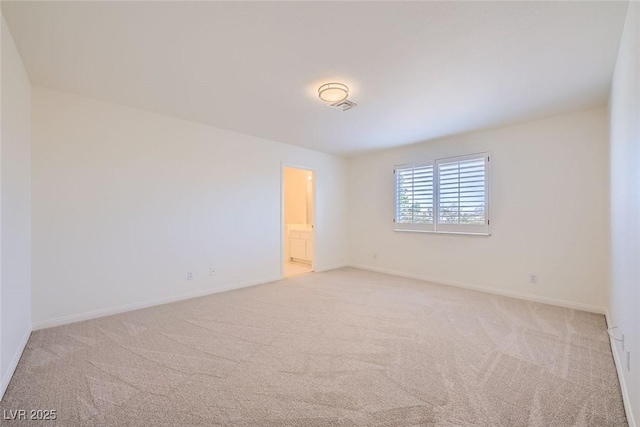 empty room featuring carpet floors, visible vents, and baseboards