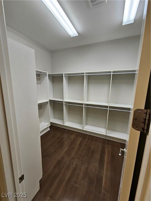 spacious closet with dark wood-type flooring and visible vents