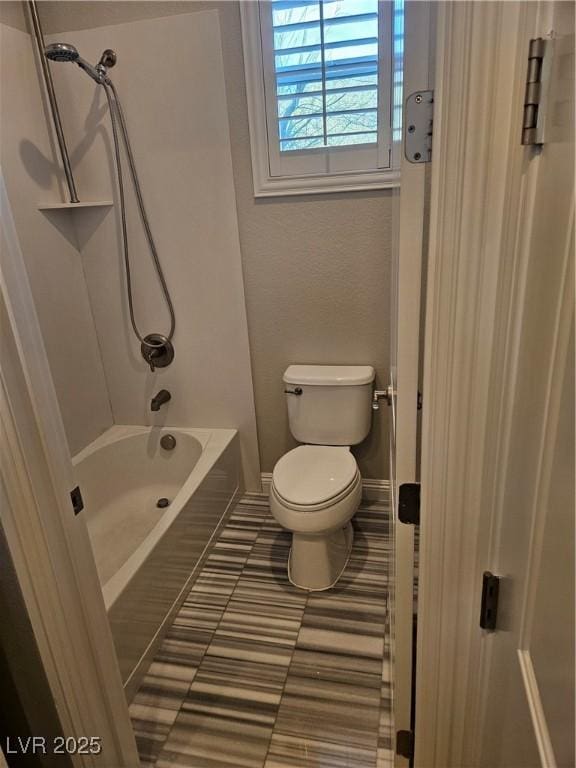 bathroom featuring tile patterned flooring, bathtub / shower combination, toilet, and baseboards