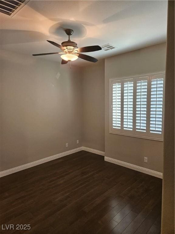 empty room with dark wood-style flooring, visible vents, ceiling fan, and baseboards