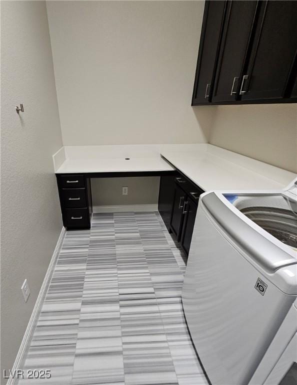 laundry room featuring washer / dryer, cabinet space, baseboards, and light tile patterned floors