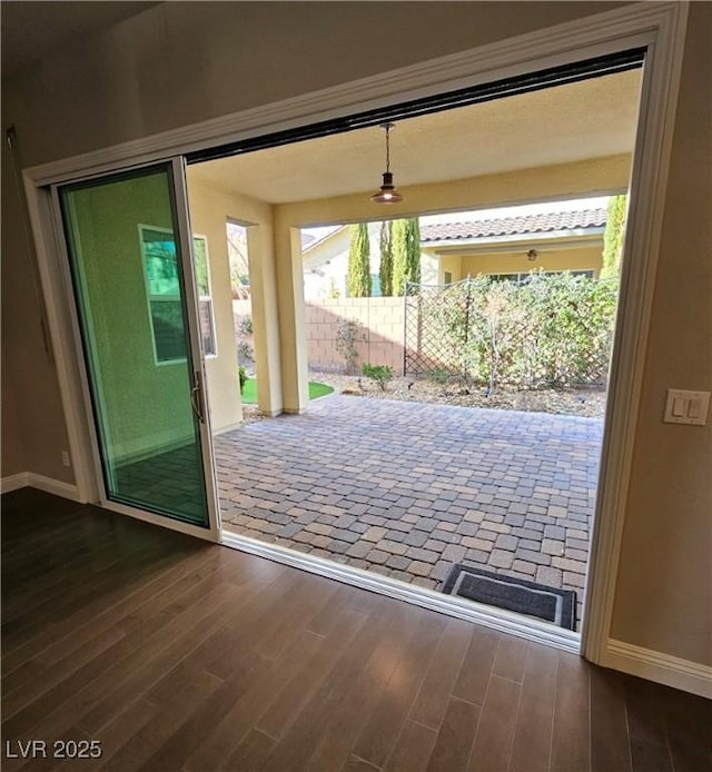 doorway featuring dark wood-type flooring and baseboards