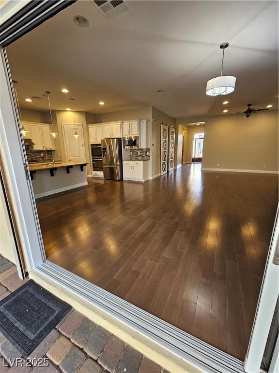 kitchen with dark wood-style flooring, visible vents, white cabinets, open floor plan, and appliances with stainless steel finishes