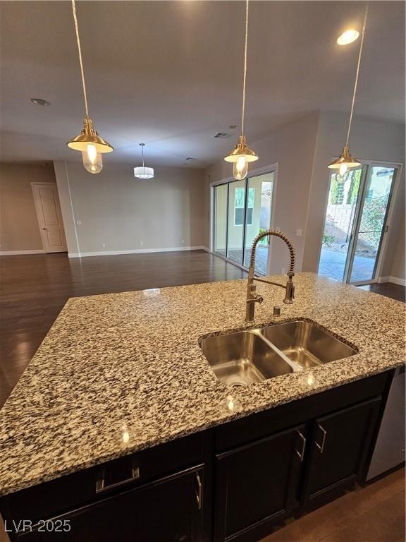 kitchen with dark cabinetry, open floor plan, and a sink