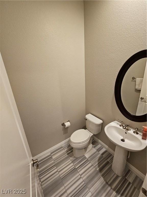 bathroom featuring toilet and baseboards