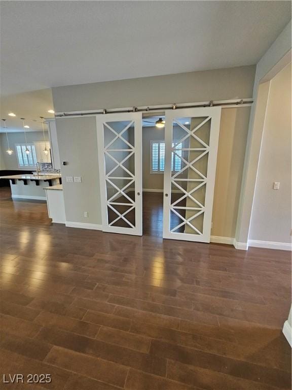 interior space featuring a barn door, plenty of natural light, and dark wood finished floors