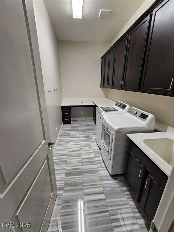 clothes washing area featuring a sink, cabinet space, baseboards, and washer and dryer