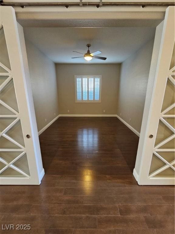 unfurnished room with wood finished floors, a ceiling fan, and baseboards