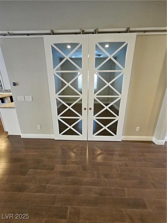 empty room with wood finished floors, baseboards, and a barn door