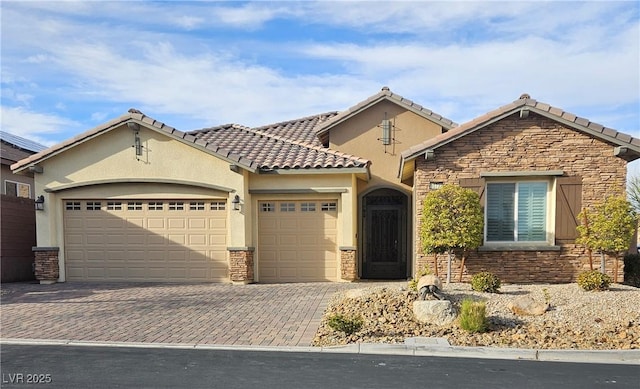 mediterranean / spanish home featuring a garage, decorative driveway, and stone siding