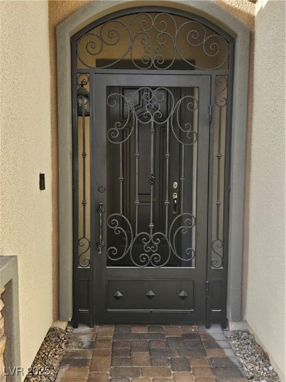 doorway to property with a gate and stucco siding