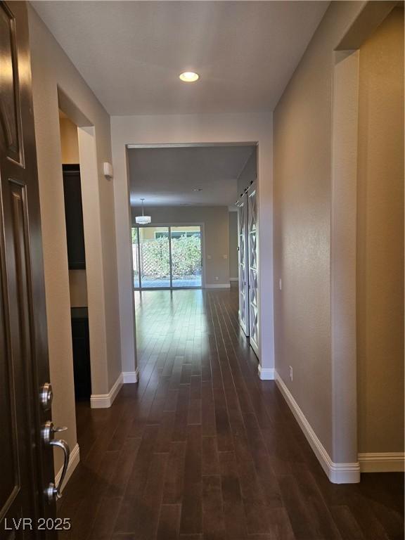 hallway featuring dark wood-style flooring and baseboards