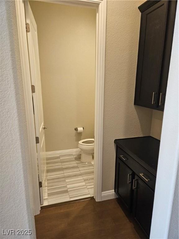 bathroom featuring wood finished floors, toilet, and baseboards