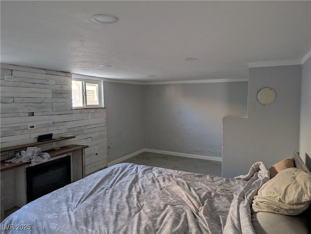 bedroom with baseboards, crown molding, and a glass covered fireplace