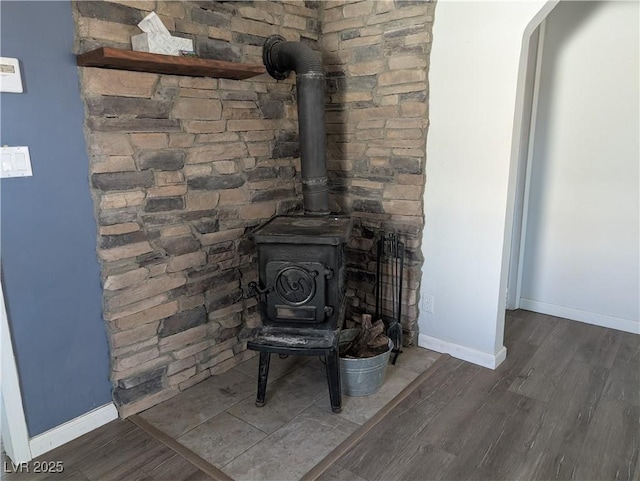 room details with wood finished floors, a wood stove, and baseboards