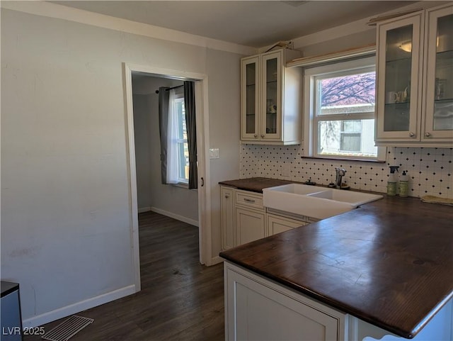 kitchen featuring baseboards, dark wood-style floors, butcher block countertops, a sink, and backsplash