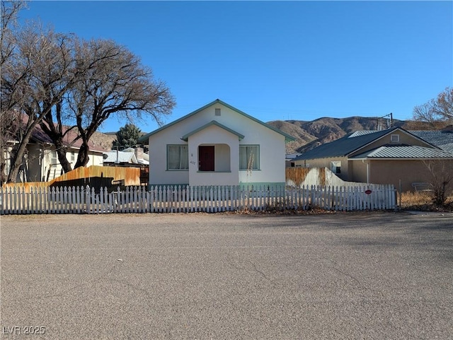 view of front of house with a fenced front yard, a mountain view, and stucco siding