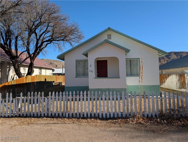 bungalow-style home with a fenced front yard and stucco siding