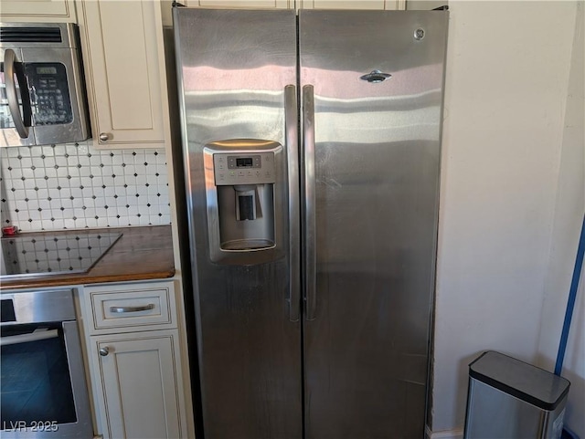 kitchen featuring appliances with stainless steel finishes, cream cabinets, and decorative backsplash