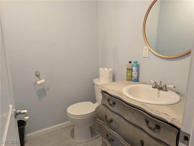 half bath featuring toilet, tile patterned flooring, baseboards, and vanity