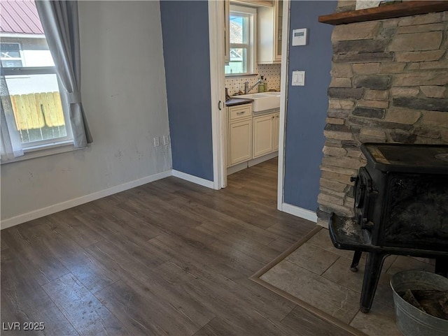 living room with a wood stove, baseboards, and dark wood-type flooring