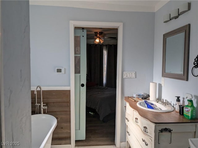 full bath featuring wood finished floors, a freestanding tub, vanity, and a ceiling fan