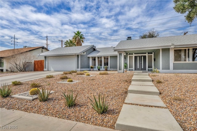 view of front of property with a garage, concrete driveway, a shingled roof, and stucco siding