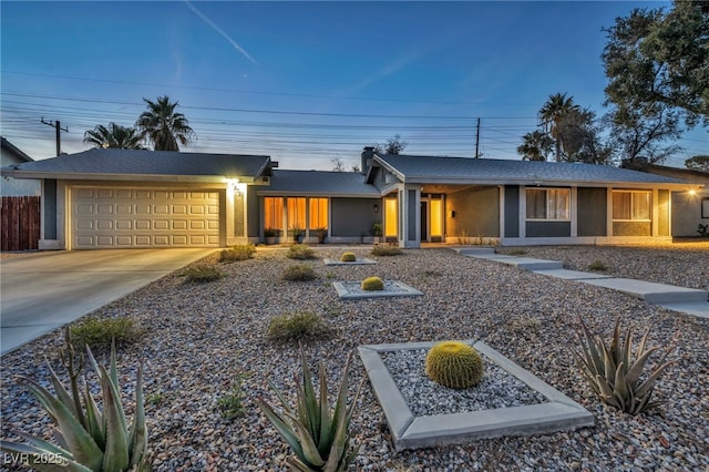 view of front of property featuring concrete driveway, an attached garage, fence, and stucco siding