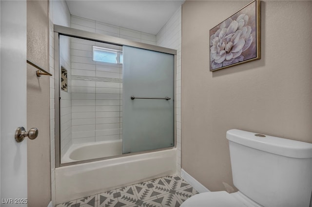 bathroom featuring baseboards, toilet, and bath / shower combo with glass door