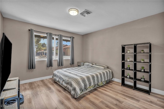 bedroom with light wood-style floors, visible vents, and baseboards