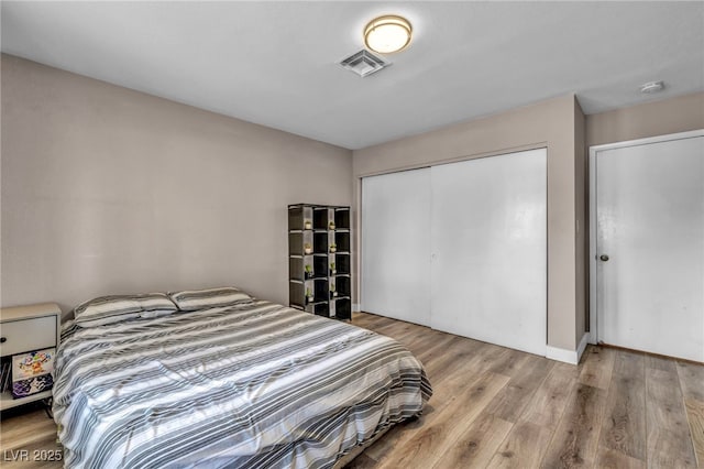 bedroom featuring baseboards, light wood-style flooring, visible vents, and a closet