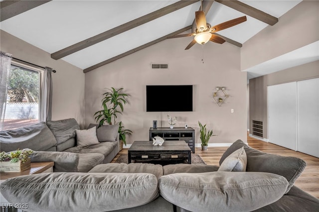 living room featuring baseboards, visible vents, beam ceiling, and wood finished floors