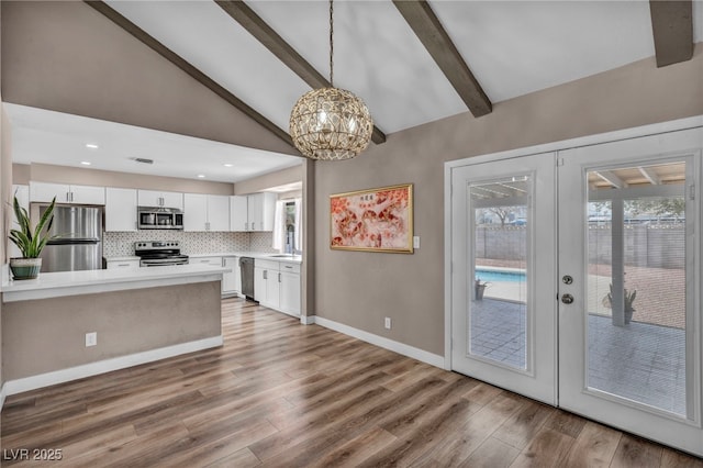 kitchen featuring french doors, vaulted ceiling with beams, stainless steel appliances, light countertops, and white cabinets