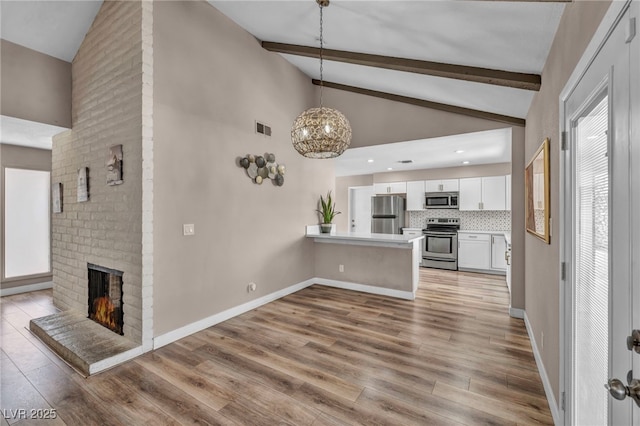 unfurnished living room with a fireplace, visible vents, baseboards, beam ceiling, and light wood finished floors