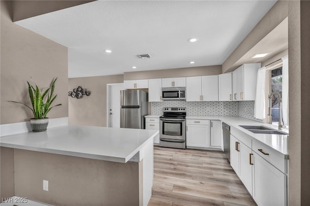 kitchen featuring stainless steel appliances, a peninsula, a sink, visible vents, and tasteful backsplash