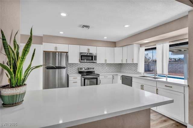 kitchen featuring appliances with stainless steel finishes, light countertops, light wood-style floors, and decorative backsplash