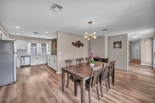 dining area with a notable chandelier, visible vents, and light wood-style floors