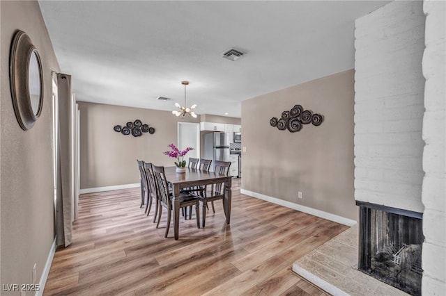 dining space featuring light wood-style floors, visible vents, baseboards, and a chandelier