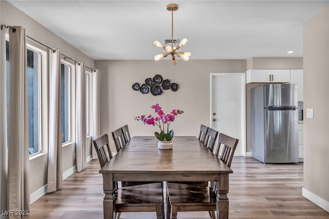 dining area featuring baseboards, a notable chandelier, visible vents, and light wood finished floors