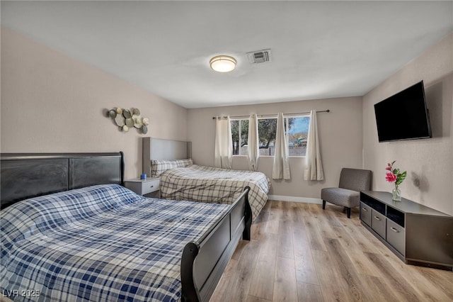 bedroom featuring light wood-style flooring, visible vents, and baseboards