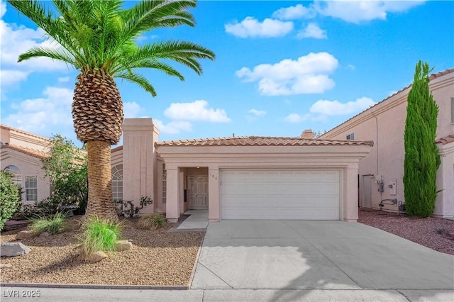 mediterranean / spanish-style home featuring concrete driveway, an attached garage, a tiled roof, and stucco siding