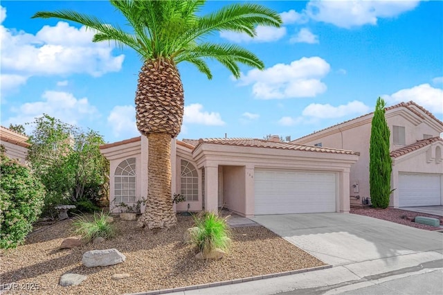 mediterranean / spanish-style house with a garage, a tile roof, concrete driveway, and stucco siding