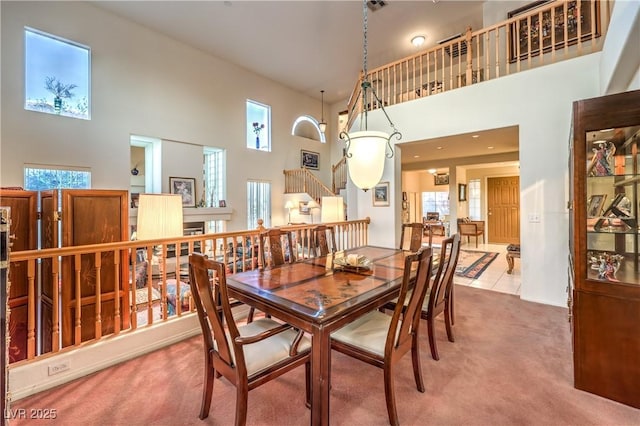 carpeted dining room featuring stairs, a high ceiling, and a wealth of natural light