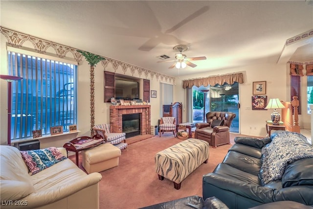 living room with visible vents, carpet flooring, a brick fireplace, and ceiling fan