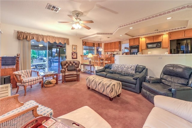 living area featuring visible vents, a ceiling fan, recessed lighting, a raised ceiling, and light colored carpet