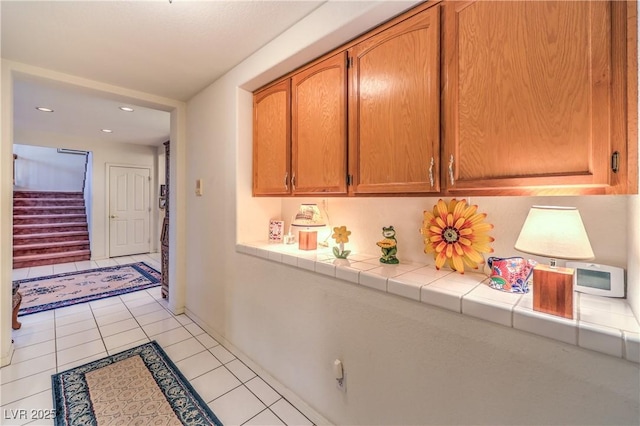 hall with light tile patterned flooring, stairway, and recessed lighting