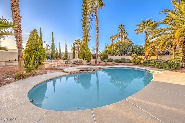 view of swimming pool featuring a patio, fence, and a pool with connected hot tub